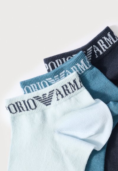 Τρία ζευγάρια διπλωμένα καλτσάκια αστραγάλου σε ανοιχτό γαλάζιο, τιρκουάζ και ναυτικό μπλε με λογότυπο και κείμενο στη μανσέτα.