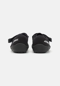 Zapatos Terrex negros con una parte superior de malla transpirable, correa ajustable y suela de goma texturizada con patrón de agarre.