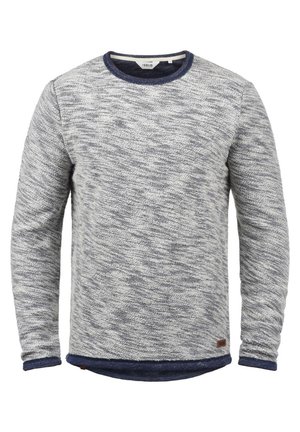 Helehall grey sviiter, millel on tumedate hallide mustrite läbisegamisega. Omab ümmargust tumesinine kraed ja varrukaotsa; sisaldab väikest pruuni logomärki.