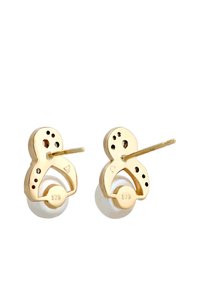 Gouden oorbellen met een unieke vorm, voorzien van een witte ronde kraal. Decoratieve gaten en accenten voegen detail toe aan het ontwerp.