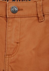 Oranje katoenen broek heeft een metalen knoop met "Blue Ridge" gegraveerd, gestikte zakken en een gladde, textuurachtige stof.