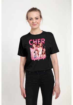 Vrouw draagt een zwart T-shirt met roze tekst "CHER" en "Ugh! As if!" met vier vrouwelijke personages in 90s-stijl outfits.