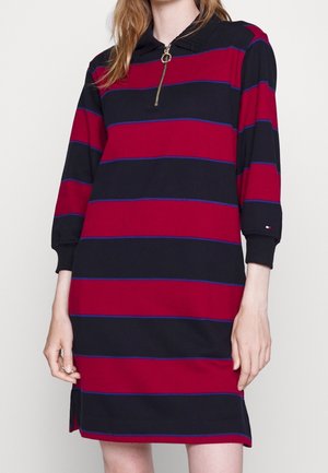 Robe rayée rouge et marine avec un col zippé, des manches trois-quarts, des fentes sur les côtés et des rayures d'accent bleues. Matière en mélange de coton.