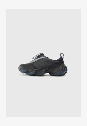Black athletic shoes with a sleek design, featuring a textured upper, gray accents, and a chunky outsole with blue traction nubs.