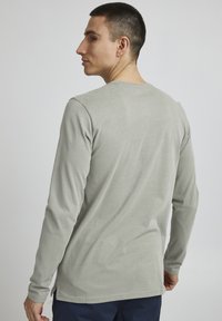 Langærmet t-shirt i lysegrå bomuld, med rund halsudskæring, lige snit og sideslit ved kanten for nem bevægelse.