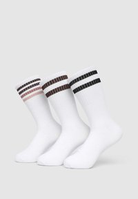 Tre paia di calzini bianchi con bande a coste, caratterizzati da strisce orizzontali in marrone scuro, marrone chiaro e nero.