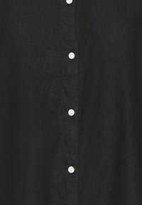 Tissu noir texturé avec une rangée verticale de cinq petits boutons blancs disposés régulièrement au centre.