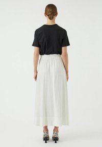 Zwarte t-shirt, witte linnen maxi rok met een elastische tailleband en zwart-wit gestreepte hakken. Gladde textuur, eenvoudig ontwerp.