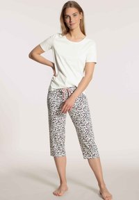 Witte kortekorte mouw top gecombineerd met geprinte broek tot halverwege de kuit met bloemenpatronen in roze, groen en zwart, met een roze trekkoord.