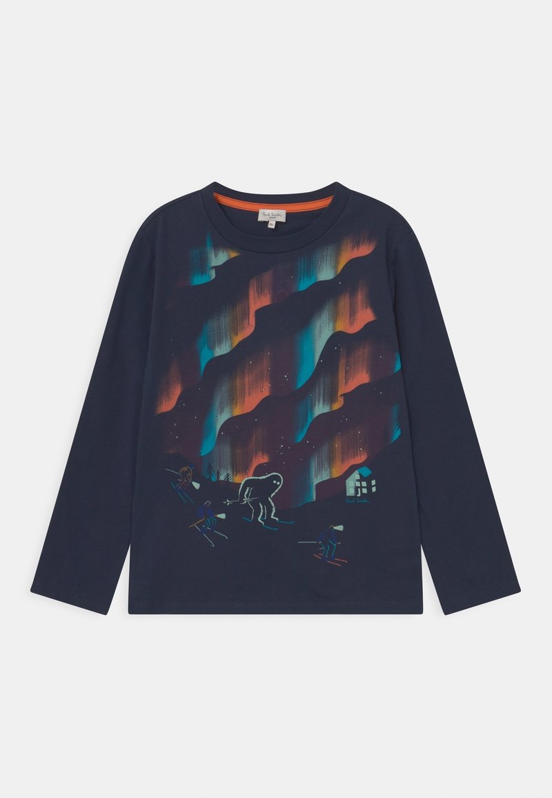 Navy pitkähihainen paita, jossa on värikkäät revontulet, hiihtäjiä otsalamppujen kanssa ja suuri hohtava olento lähellä mökkiä.