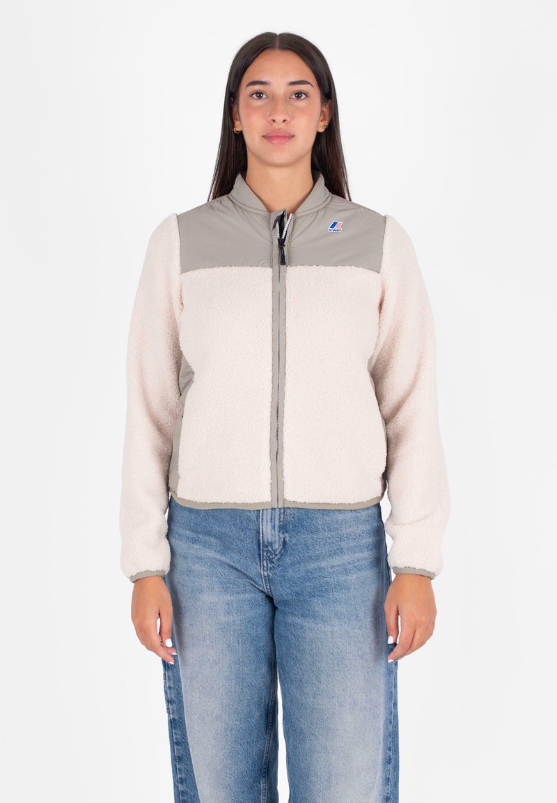 Lichte, crème fleece jas met grijze nylon accenten, ritssluiting en elastische manchetten. Bevat een klein logo op de borst.