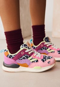 Baskets colorées présentant des motifs rose, violet et à imprimé animal. Fabriquées en tissu et en daim, avec des accents texturés et une semelle tachetée.