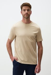 T-shirt beige a manica corta realizzato in tessuto liscio con scollatura rotonda, caratterizzato da una vestibilità regolare e cuciture minime.