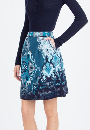 Knie-lange rok met geometrische patronen in blauwe en zwarte tinten. Heeft een getailleerde taille met zakken, gemaakt van een gestructureerde stof.