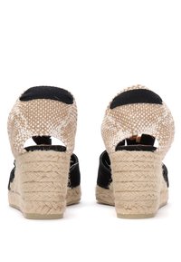 Sorte espadrille kile sandaler har en vevd halmgir langs hælen, åpen bakdesign og et teksturert stoffoverdel med lyse beige detaljer.