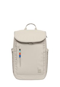 Sac à dos en tissu beige avec un rabat, poche zippée à l'avant et poches latérales. Présente une étiquette colorée et le nom de la marque "GOT BAG."