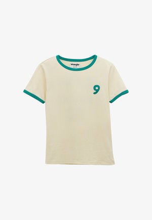 Cremfarbenes T-Shirt mit kurzen Ärmeln und grüner Einfassung am Kragen und an den Ärmeln, mit einem grünen, gestickten Komma auf der linken Brustseite.