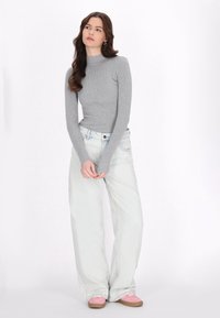Graues geripptes Langarmoberteil kombiniert mit hellblauen weiten Jeans und rosa Schuhen. Einfaches Design mit einer figurbetonten Silhouette und weichem Stoff.