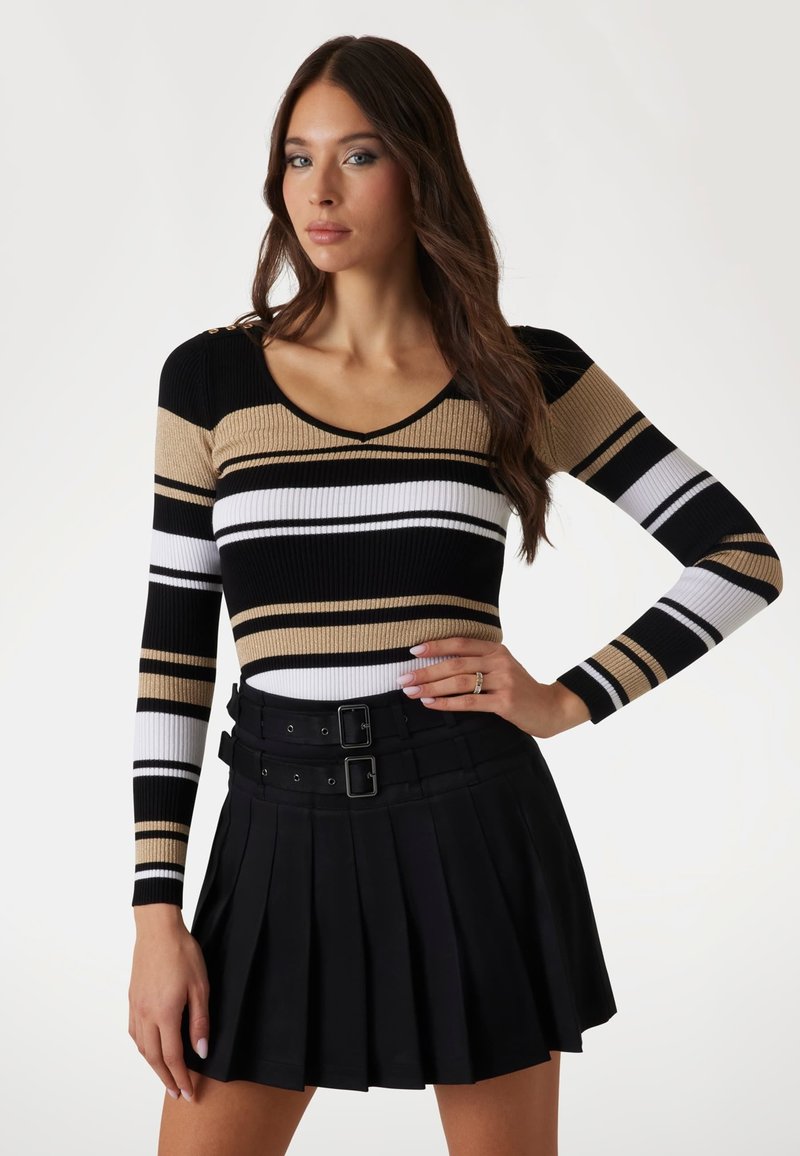 Haut à manches longues en ribbed avec des rayures verticales noires, blanches et brunes, et un col en V. Assorti à une jupe plissée noire avec des détails en boucle.
