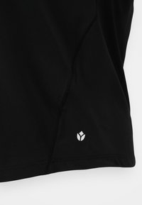 Crna atletska majica s glatkom teksturom, zakrivljenim šavovima i bijelim logotipom na donjoj strani. Materijal izgleda lagano i fleksibilno.