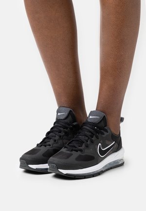 Czarne buty sportowe z siateczkową cholewką, białym logo Nike oraz widoczną poduszką powietrzną na białej podeszwie. Teksturowane akcenty podkreślają design.