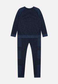 Conjunto de ropa deportiva en azul marino que incluye una parte superior de manga larga y leggings a juego con una textura sutil y detalles de paneles en contraste.