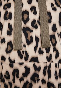 Tessuto con stampa leopardata in beige, con macchie nere. Due spalline grigie texturizzate. Tessuto morbido a costine con una tasca visibile sul fondo.