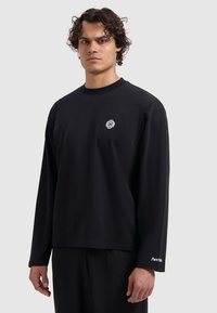 Black long-sleeve t-shirt made of cotton with a round neckline, featuring a small white logo on the chest and brand text on the sleeve.