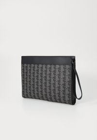 Sort clutch-taske lavet af tekstureret materiale med et geometrisk mønster. Den har en flad form og en slank håndledsrem til at bære.