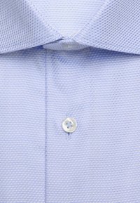 Chemise bleu clair avec un motif tissé texturé, comportant un col pointu et un seul bouton avant fermé.