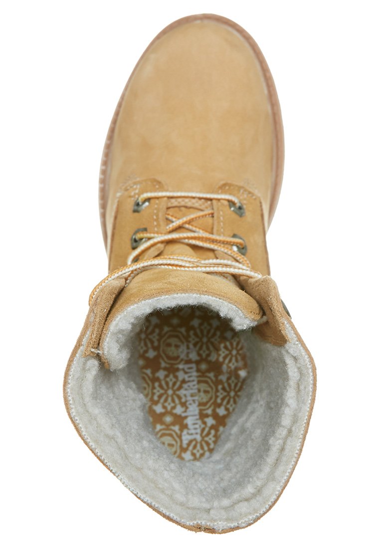 Bottine en daim beige à bout rond, lacets texturés beige et doublure en peluche. La semelle intérieure présente un design à motifs avec des motifs de crânes.