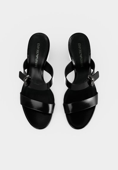 Μαύρα σανδάλια με ανοιχτά δάχτυλα, φαρδύ λουράκι μπροστά και λουράκι στον αστράγαλο με αγκράφα, επίπεδη σόλα και λογότυπο Emporio Armani στην εσωτερική σόλα.