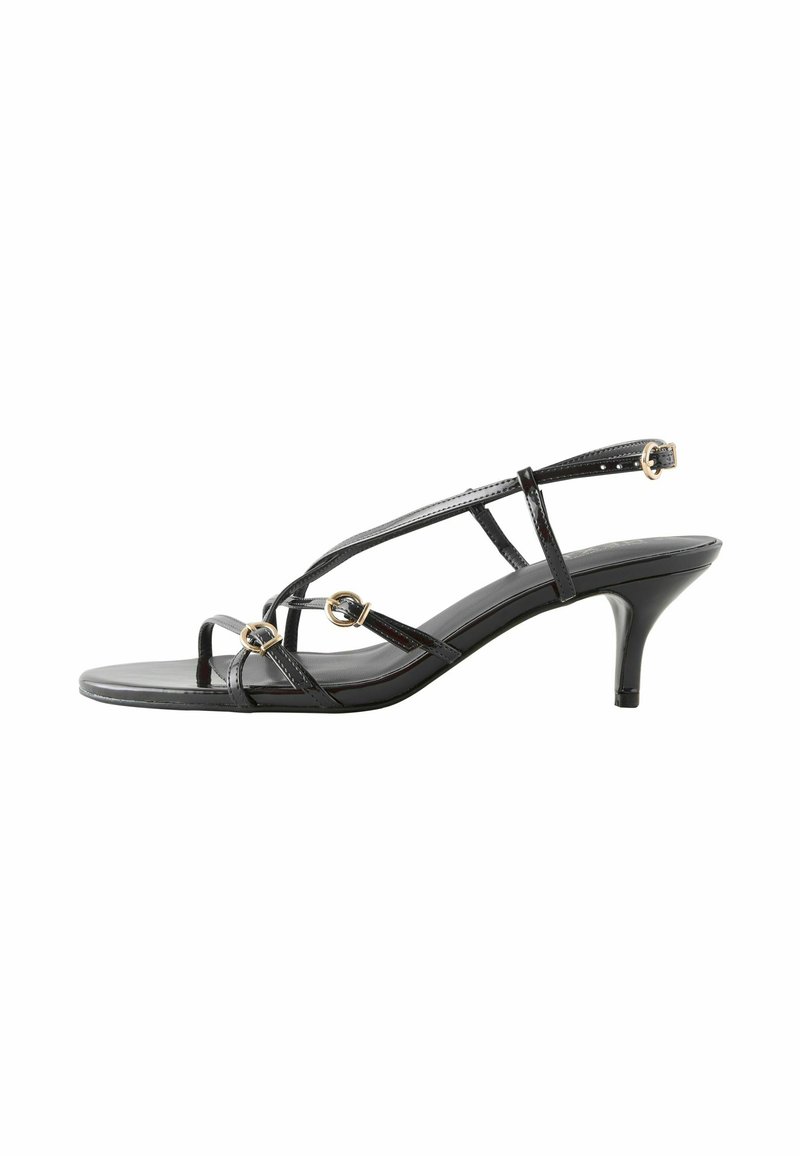 Sorte patentlæder sandaler med tynde stropper, der har gyldne cirkulære detaljer og en lav hæl. Åben tå design med en minimalistisk silhuet.
