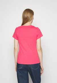 Camiseta de algodón de cuello redondo y mangas cortas en un brillante color rosa, con un ajuste cómodo y un reverso liso sin gráficos ni patrones.