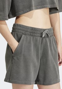 Gray, textured cotton shorts with an elastic waistband, drawstring, and side pockets, featuring a relaxed fit and hem reaching mid-thigh.