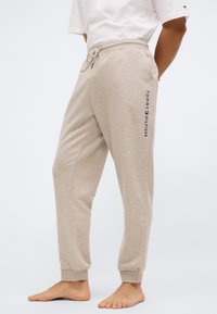 Beige sweatpants gemaakt van een zachte katoenmix, met een tailleband met trekkoord, boordjes aan de enkels en een geborduurd logo aan de linkerkant.