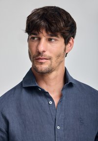 Korte mouwen, marineblauw linnen overhemd met een button-down kraag en een klein geborduurd logo op de borst. Zachte textuur en een ontspannen pasvorm.