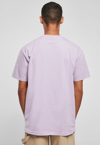 Rövid ujjú t-shirt világos levendula színű pamutból, kerek nyakkivágással és laza fazonnal, sima textúrával és látható grafikák nélkül.