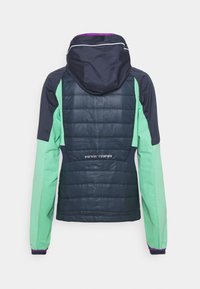 Huvtröja med en blandning av marinblått, grönt och lila; puffig mittdel; slät textur; har logotyp på baksidan.