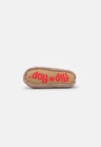 Toy slipper, tan plush exterior with fuzzy texture. Printed red text on a beige base with polka dots. Rounded shape, soft and flexible design.