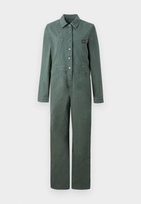 Combinaison en coton vert avec manches longues, boutons à l'avant, deux poches poitrine et une coupe droite. Comprend un patch logo sur la poitrine.