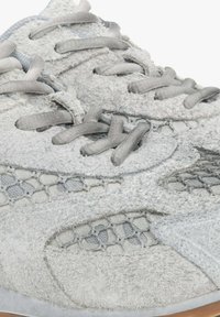 Grijze sportieve schoen met een textuur van suède bovenwerk, gaasaccenten en platte grijze veters. De zool heeft een duurzame rubberen afwerking.