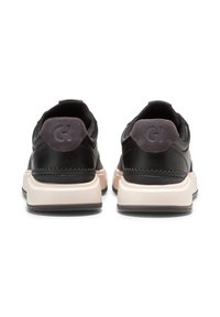 Černé kožené tenisky s světle růžovou podrážkou, s šedým semišovým patkem a embosovaným logem na zadní straně. Hladký povrch a zaoblený tvar.