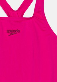 Roze zwemkleding met een racerback ontwerp. Gemaakt van gladde, rekbare stof met een contrasterend zwart 'speedo' logo op de borst.