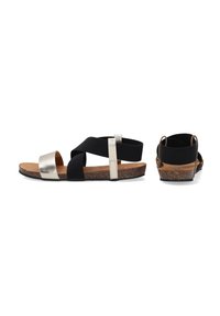 Zwarte en zilveren sandalen met een kurken zool, voorzien van kruislings verbonden bandjes en een metallic accent. Gladde textuur met een plat ontwerp.