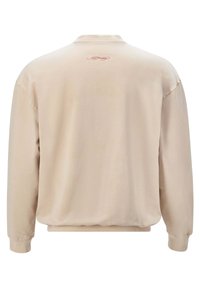 Felpa beige con vestibilità morbida, colletto rotondo e polsini a coste. Presenta un piccolo logo testuale decorativo rosso sulla parte superiore della schiena.