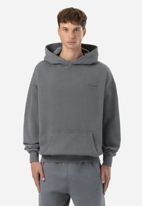Grauer Baumwoll-Hoodie mit einer Kängurutasche und gerippten Bündchen. Verfügt über eine große Kapuze und dezente Branding auf der Brust. Lockerer Schnitt.