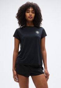 Μαύρο αθλητικό κοντομάνικο με στρογγυλή λαιμόκοψη. Διαθέτει μικρό λευκό λογότυπο στο αριστερό στήθος. Λείο, ελαφρύ ύφασμα.