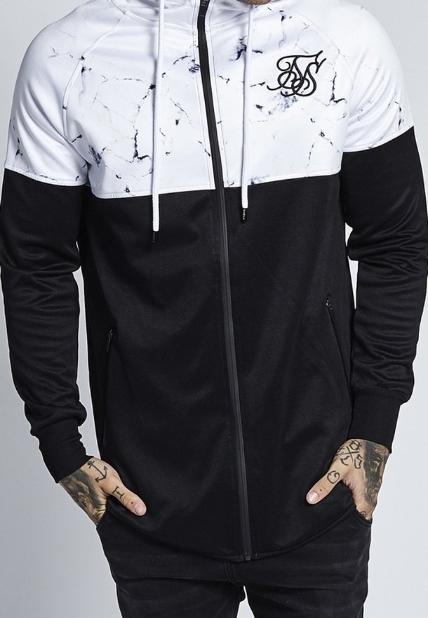 Svart och vit jacka med ett marmormönster på toppen, med dragkedja fram, två sidofickor och en logotyp på bröstet.
