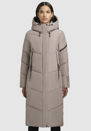 Pitkä, vaalea beige puffatakki, jossa on korkea kaulus, vetoketjulliset taskut ja vettä hylkivä chevron-kuvio. Sisältää kiristysnauhan hupun ja sivunapit.